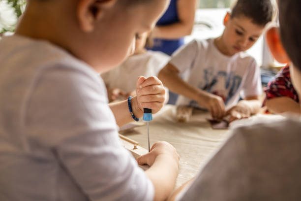 istock Group of kids in elementary school making school project with wooden pieces 1360713473