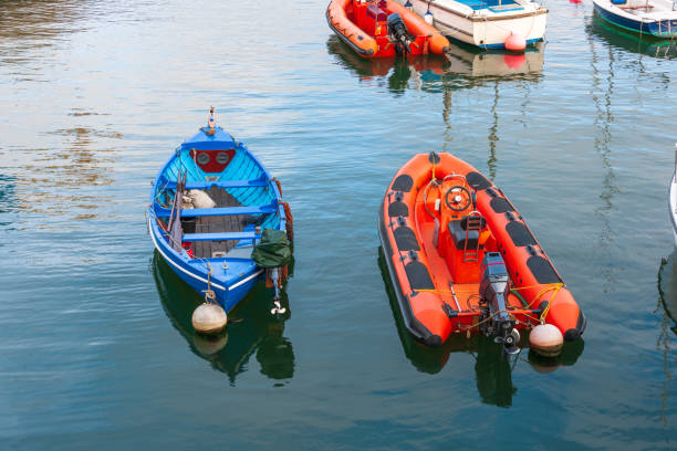 Modern grey inflatable robust durable flatbeat fiberglass dinghy boat with white leather seats and high quality central steering column anchored in local harbor surrounded with calm blue sea on warm sunny spring day