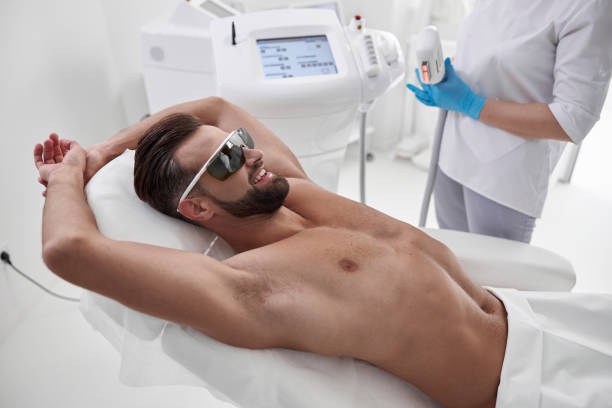 istock Happy man with protective goggles lies on couch while master prepares equipment in salon 1360716175