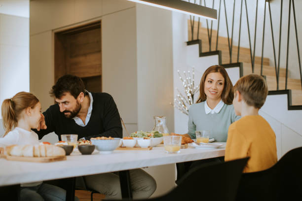 istock Young happy family talking while having breakfast at dining table 1360718320