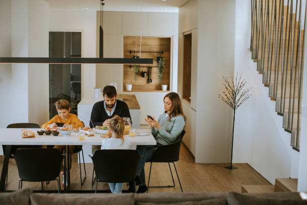 istock Family using mobile phones while having breakfast at dining table at apartment 1360718322