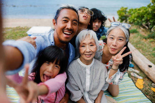 Family selfie moment Family having a picnic at the beach and taking selfies asian mom picnic stock pictures, royalty-free photos & images