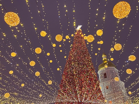 Christmas tree decorated golden illuminated balls near ancient  St. Sophia's Cathedral in Kyiv city, capital of Ukraine. Christmas and New Year celebration.