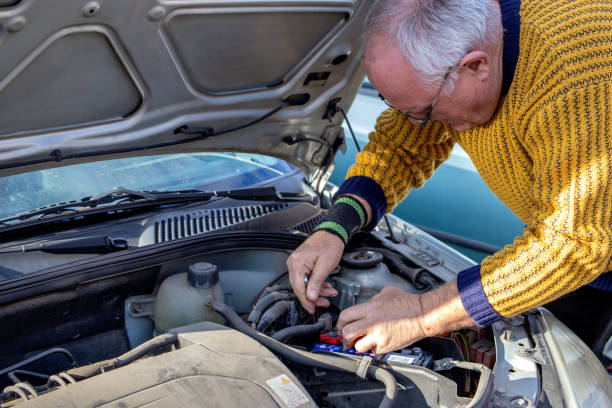 senior mechanic worker checking and changing a car battery. - old men car oil imagens e fotografias de stock