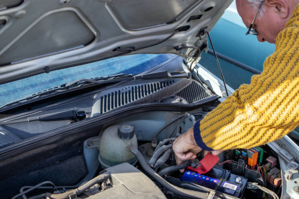 senior mechanic worker checking and changing a car battery. - old men car oil imagens e fotografias de stock