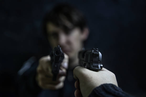 istock Man's hand with pistol pointed at criminal with revolver. 1360731252