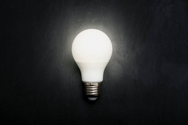 Hand reaching out to light in black, hopeful concept