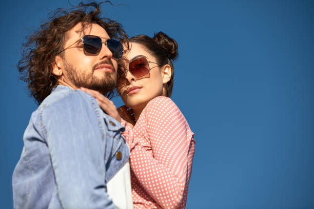 Fashion models couple wearing sunglasses. Sexy woman and handsome young man portrait over light background. Attractive fashion Boy and girl posing. Hairstyle, haircut, glasses stock photo