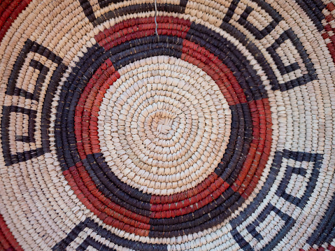 Close up of a Native American woven basket with geometric patterns in rust and black.