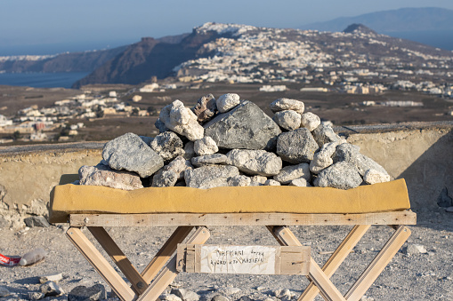 Cairn on Pyrgos Kallistis in Santorini, Greece. The chair appears to have been placed at the summit of Pyrgos Kallistis for people to rest and enjoy the view of Santorini. The rocks appear to have been placed by tourists reaching the summit.