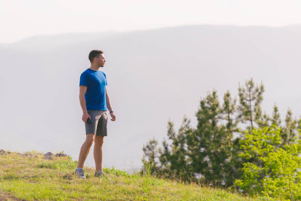 istock A fit male athlete is preparing for a work out in nature while looking over a cliff at the large lake and mountain line. 1360739663