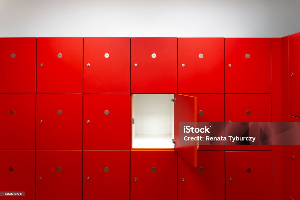 Deposit red locker boxes or gym lockers inside of a room with one central opened door Locker Stock Photo