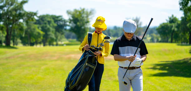 Portrait of Confidence Asian man golfer holding golf club hitting golf ball on the green at golf course in sunny day. Healthy male enjoy outdoor lifestyle activity sport golfing at country club on summer vacation