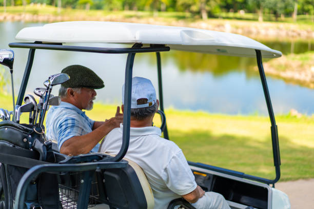 夏の晴れた日にゴルフコースでゴルフカートを運転するアジアのシニア男の友人 - golf cart golf bag horizontal outdoors ストックフォトと画像