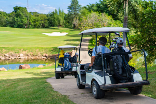 gruppo di uomo anziano asiatico che guida il golf cart sul campo da golf nella giornata di sole estiva - golf foto e immagini stock