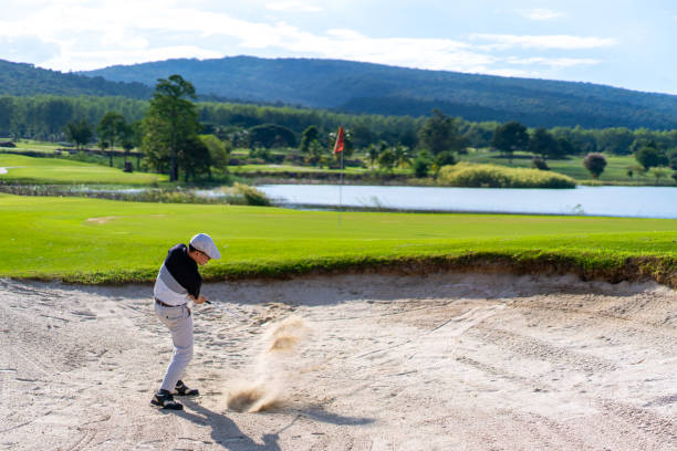 istock Asian man hitting golf ball from a bunker to the green at golf course 1360744195