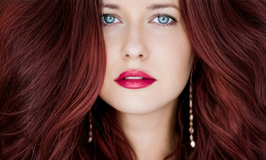Hairstyle model and beauty face closeup. Beautiful woman with long straight dark red hair styled in curly waves, classic glamour style and luxury fashion portrait.