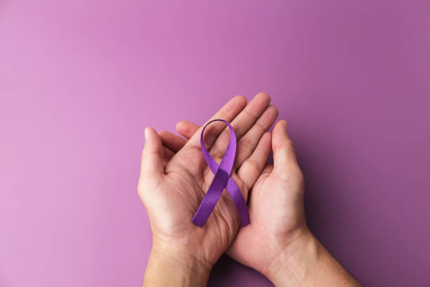 istock Hands holding Purple ribbons on a purple background. 1360758019