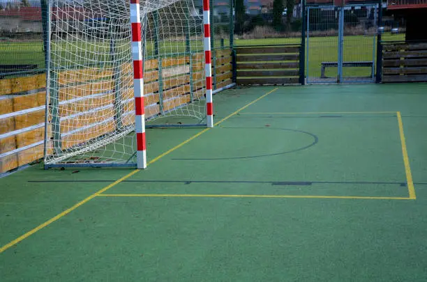 multifunctional outdoor playground for ball games at school. green artificial turf from a plastic carpet with lines. basketball hoops and soccer goals. around the grabbing high net and guardrails , tartan, guardrails