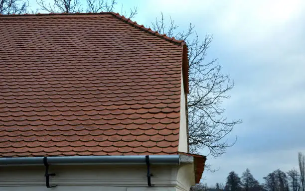 Photo of view of the roof made of red brick burnt tiles of the beaver type used in Central Europe on all historical roofs, especially in Austria. the bags overlap several times, they look like beaver teeth