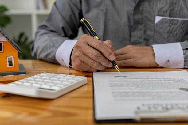 istock Man checking documents on table, housing salesman checking for correctness of contract documents before bringing customers to sign the deal. Real estate trading concept. 1360771323