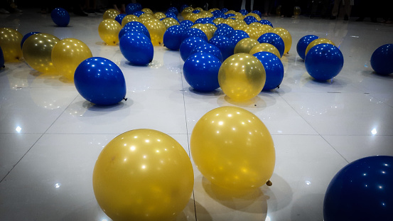 After the festive and fun party, yellow and blue balloons are scattered on the floor