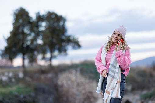 Happy young woman talking on phone in nature