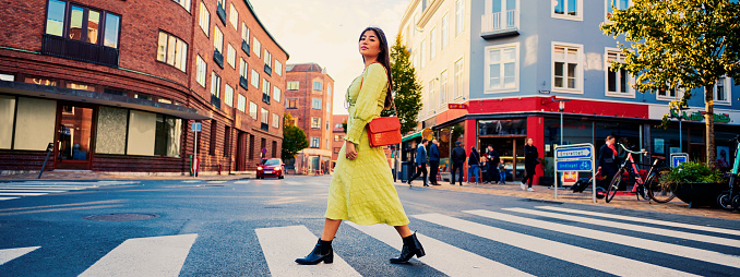 Model outdoors in city. Horizontal banner wide format. Low angle view of woman crossing street