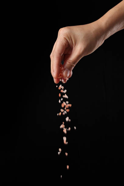 istock Hand holding pink salt on black background 1360786618