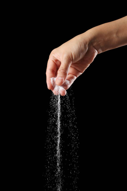 Hand holding salt on black background stock photo