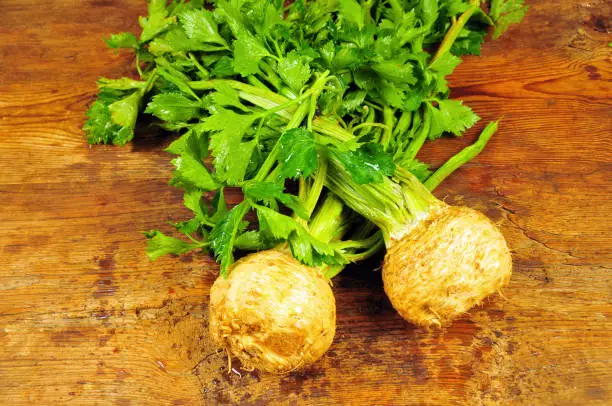 Fresh organic celery with roots on wooden table