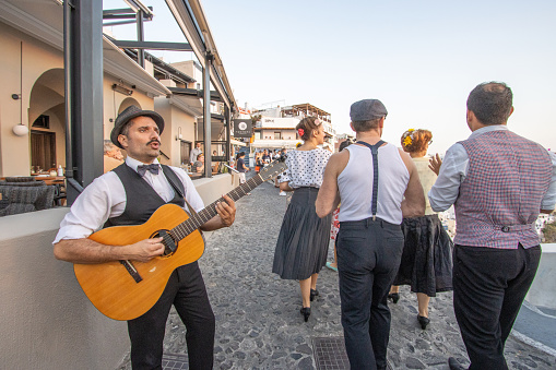 A musician from the theatre play The Greek Wedding Show plays guitar in the streets of Firá on Santorini, Greece, advertising their play