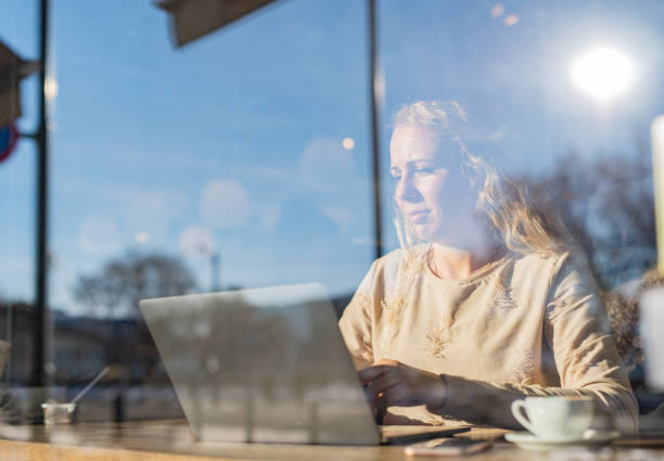 istock Woman using laptop in coffee shop 1360798221