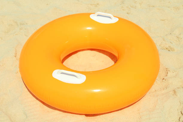 istock Orange children's circle for swimming on a sandy beach. Close-up. 1360808065