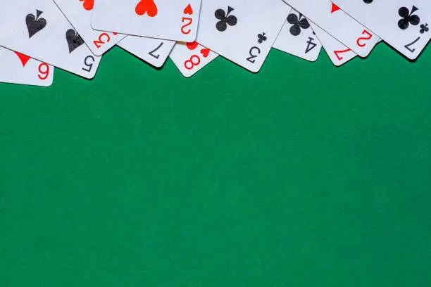 Playing cards on green felt table. Background with copy space in center