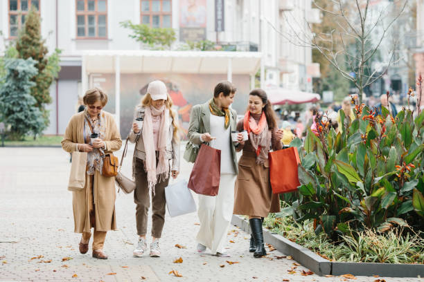 街を歩きながら買い物袋を持つ笑顔の大人の女性のグループ - bag senior adult outdoors friendship ストックフォトと画像