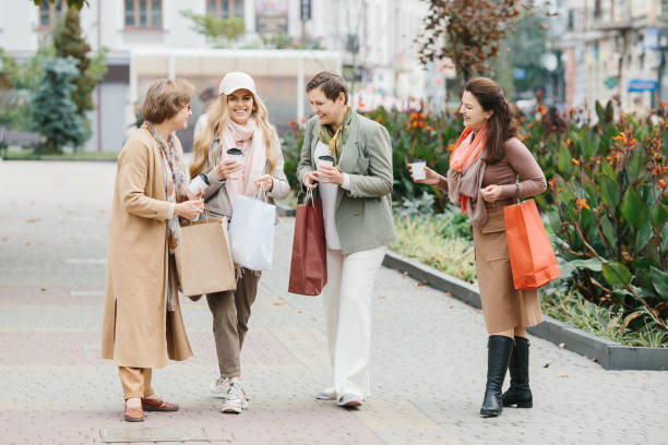 街を歩きながら買い物袋を持つ笑顔の大人の女性のグループ - bag senior adult outdoors friendship ストックフォトと画像