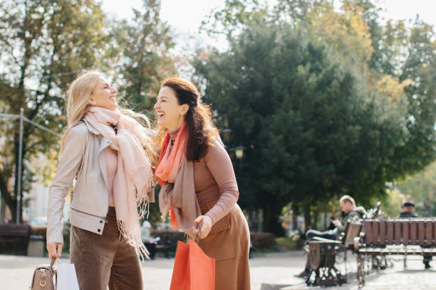 街の通りを歩きながら買い物について話し合う先輩女性のガールフレンド。 - bag senior adult outdoors friendship ストックフォトと画像
