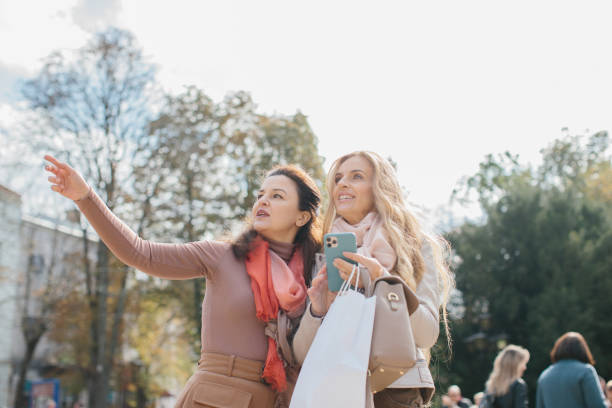 街の通りを歩きながら買い物について話し合う先輩女性のガールフレンド。 - bag senior adult outdoors friendship ストックフォトと画像