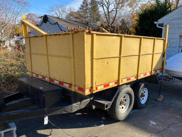 Yellow dumpster on a black trailer in a homes driveway stock photo