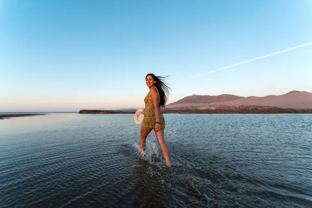 young latin woman walking on through water happy and smiling outdoors, looking at the camera, back view young latin woman walking on through water happy and smiling outdoors, looking at the camera, back view chile tourist stock pictures, royalty-free photos & images