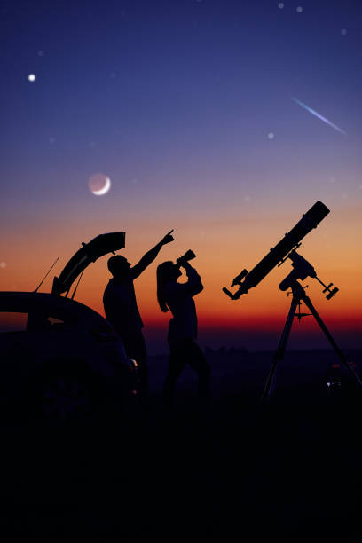 istock Couple stargazing together with a astronomical telescope. 1360818519