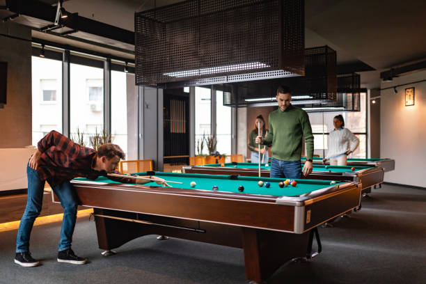 istock Two men play pool, while behind them are two women who also play billiards and have fun. 1360818621