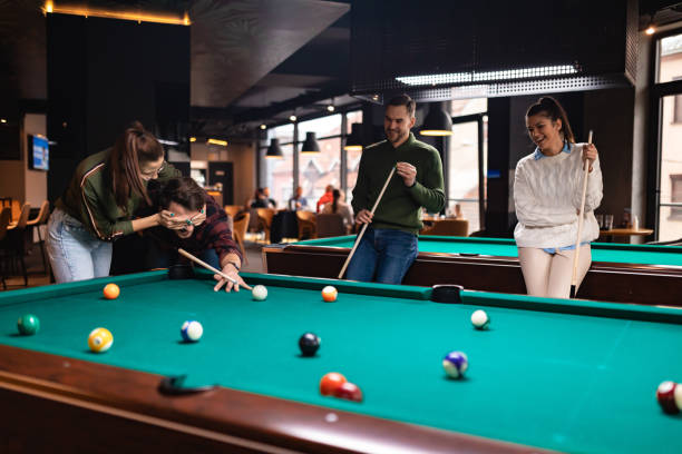 istock Two young loving couples playing billiards against each other and having fun. 1360818763