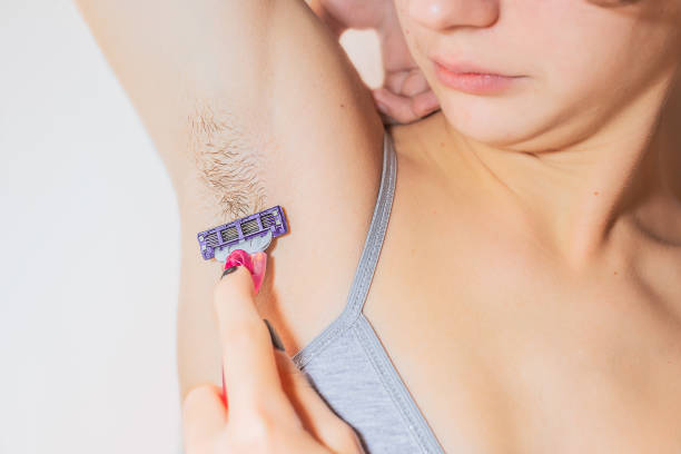 Young teen girl shaves her armpit hair for the first time Caucasian young woman teenager shaves her armpit hair with straight razor in her hand Very Peri color body hair stock pictures, royalty-free photos & images