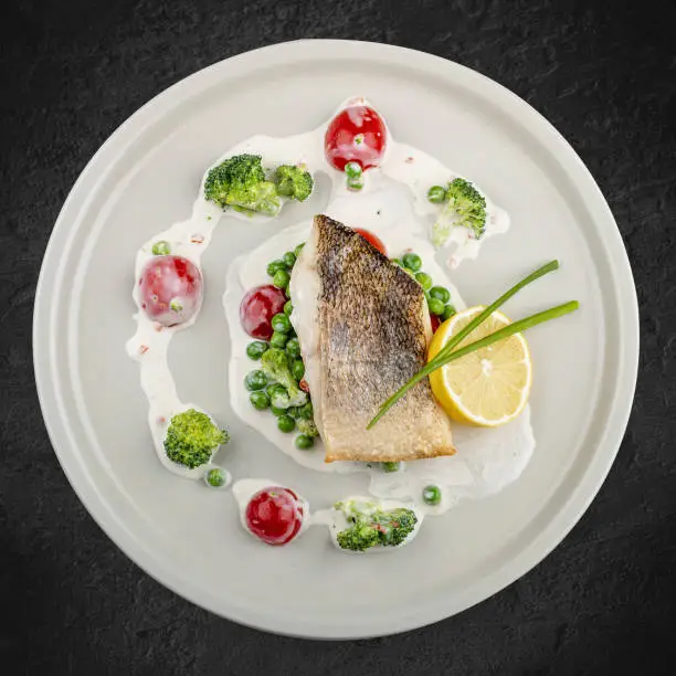 Photo of Pike perch on a vegetable pillow . Isolated on a black background.