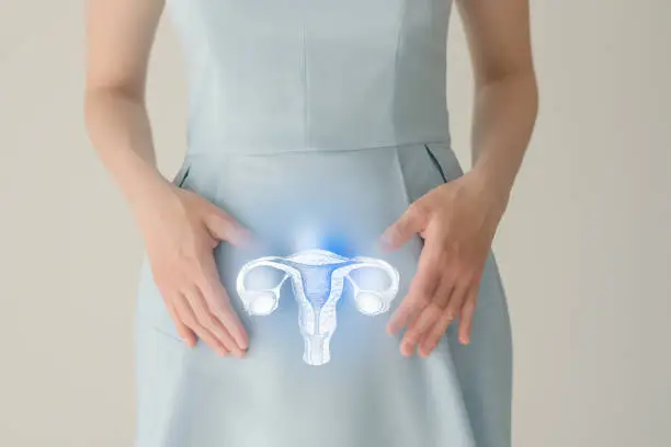 Unrecognizable female patient in blue clothes, highlighted handrawn uterus in hands. Human reproductive system issues concept.