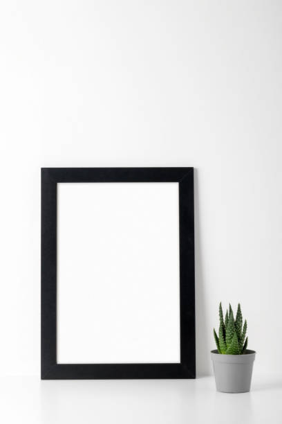 istock A mock-up of a picture frame with a black wooden frame on a white table, a small succulent. Show text or product. 1360822408