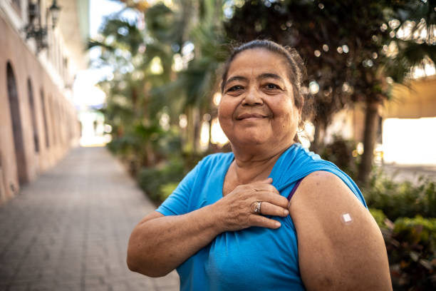 Portrait of a senior woman vaccinated showing her arm with a bandage outdoors Portrait of a senior woman vaccinated showing her arm with a bandage outdoors rolled up sleeves stock pictures, royalty-free photos & images