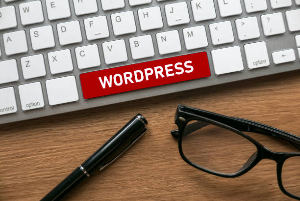 Pen. glasses and computer keyboard with a red button written with Wordpress. stock photo